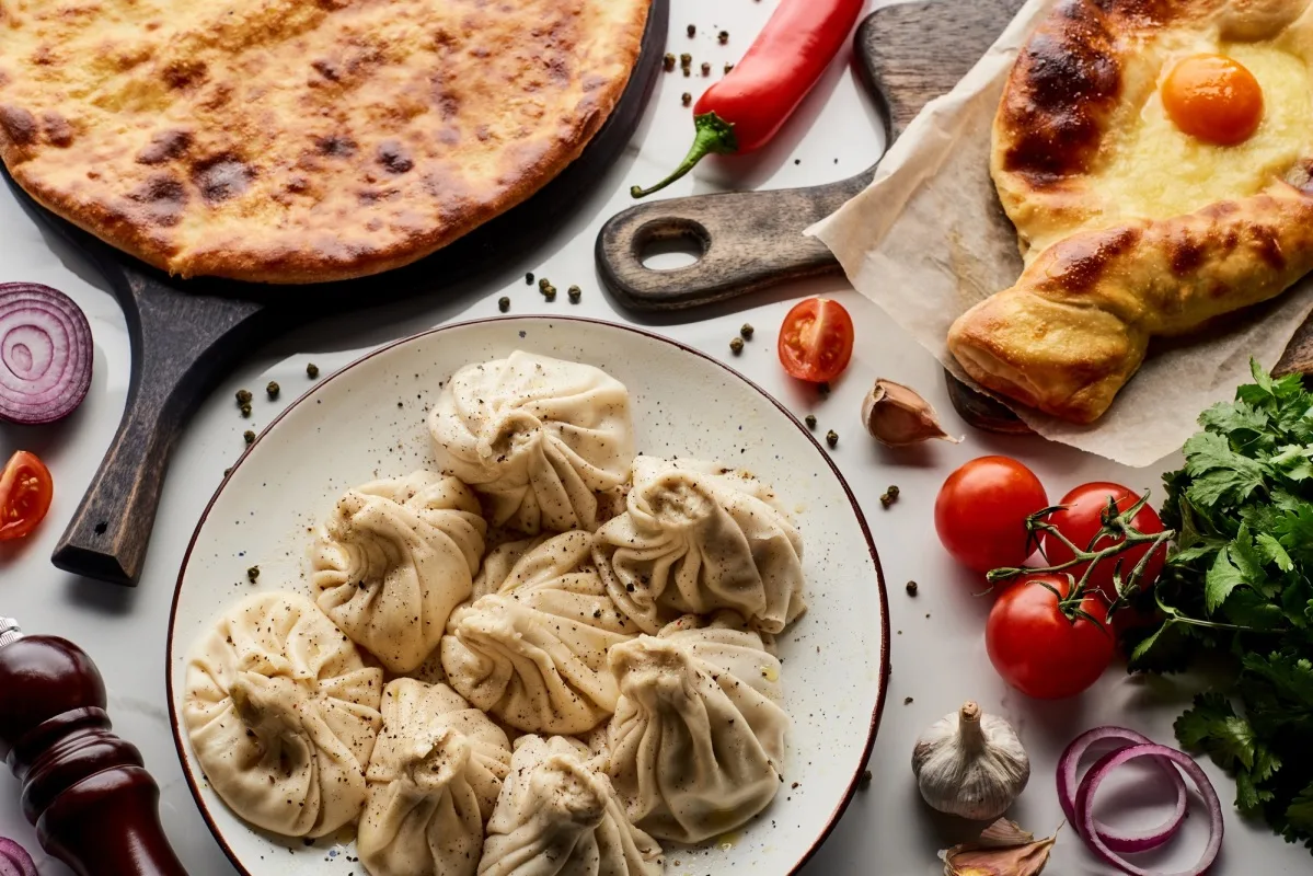 vue de dessus de délicieux khinkali et khachapuri près de légumes et d'épices sur une table en marbre