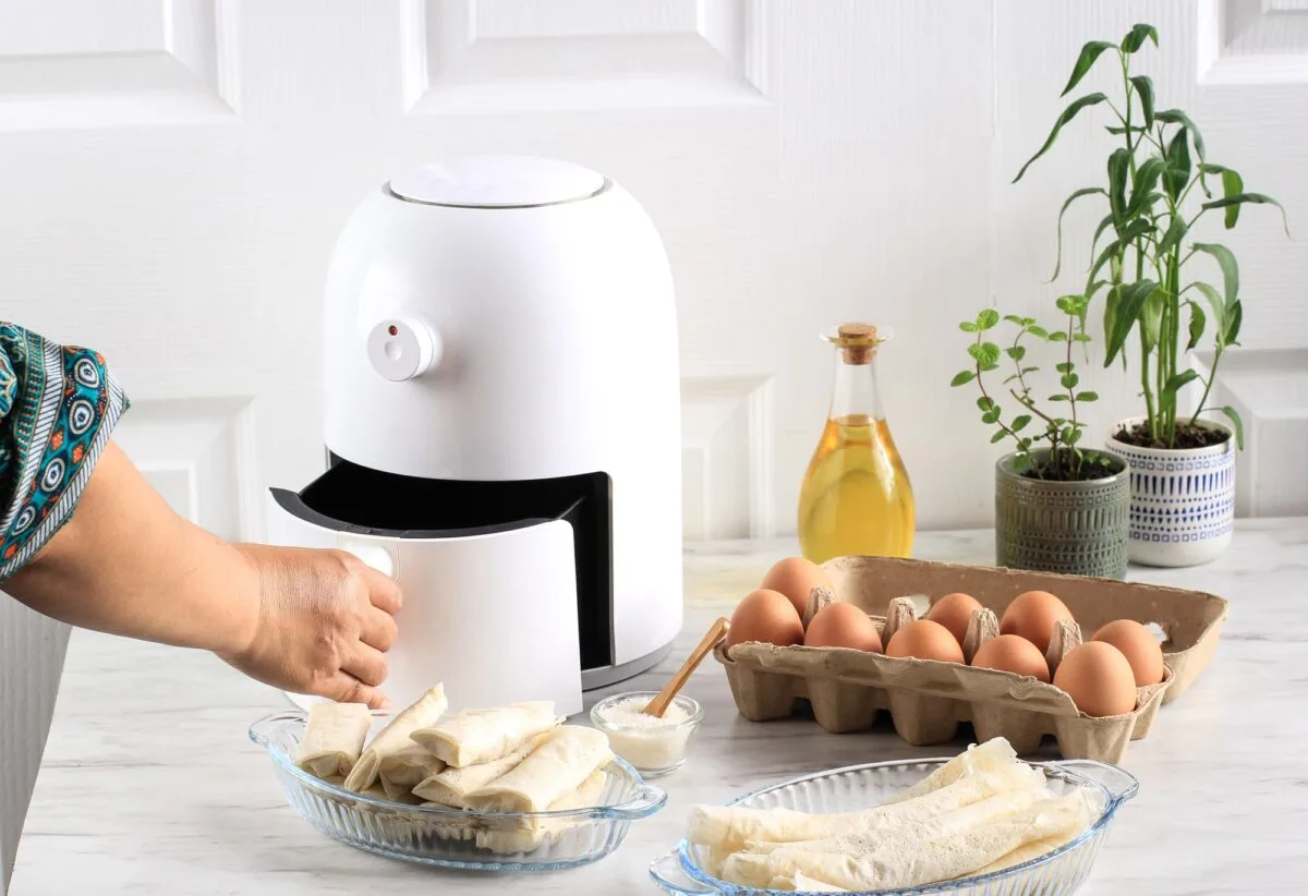Woman Hand Open Airfryer Tray. A White Deep Fryer or Oil Free Fryer Appliance