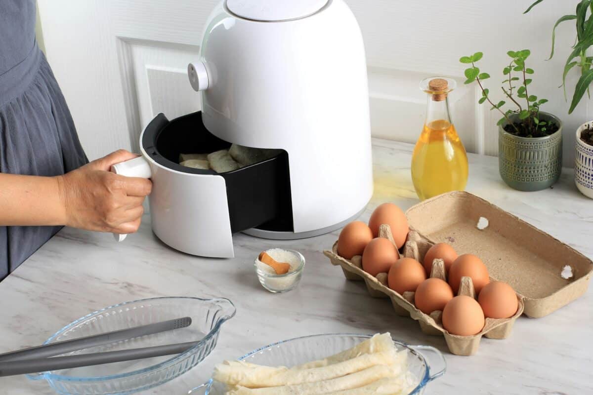Woman Hand Open Airfryer Tray. A White Deep Fryer or Oil Free Fryer Appliance