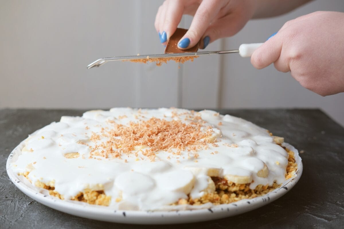 woman's hands grating chocolate on Banoffee pie