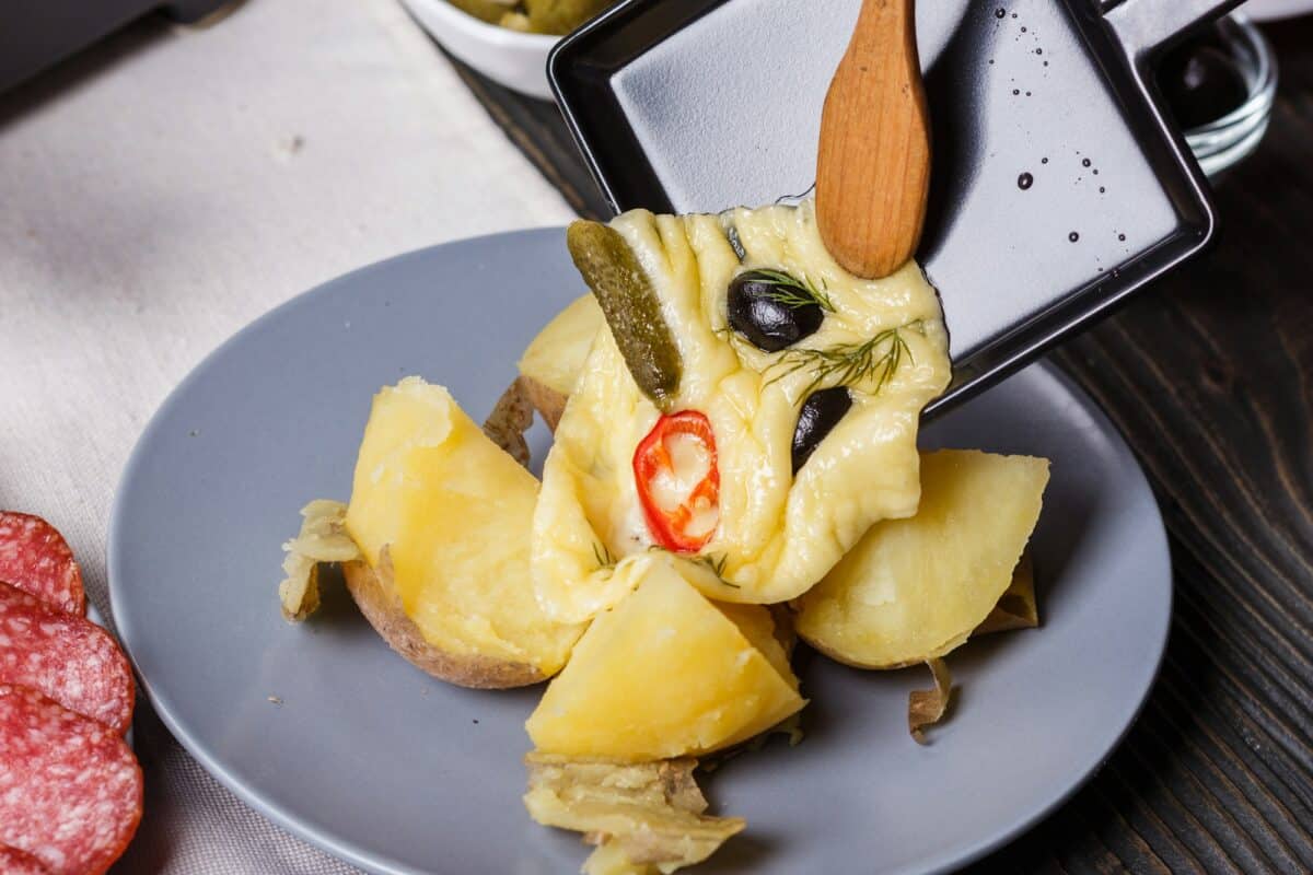 young woman is preparing a traditional Swiss cheese raclette